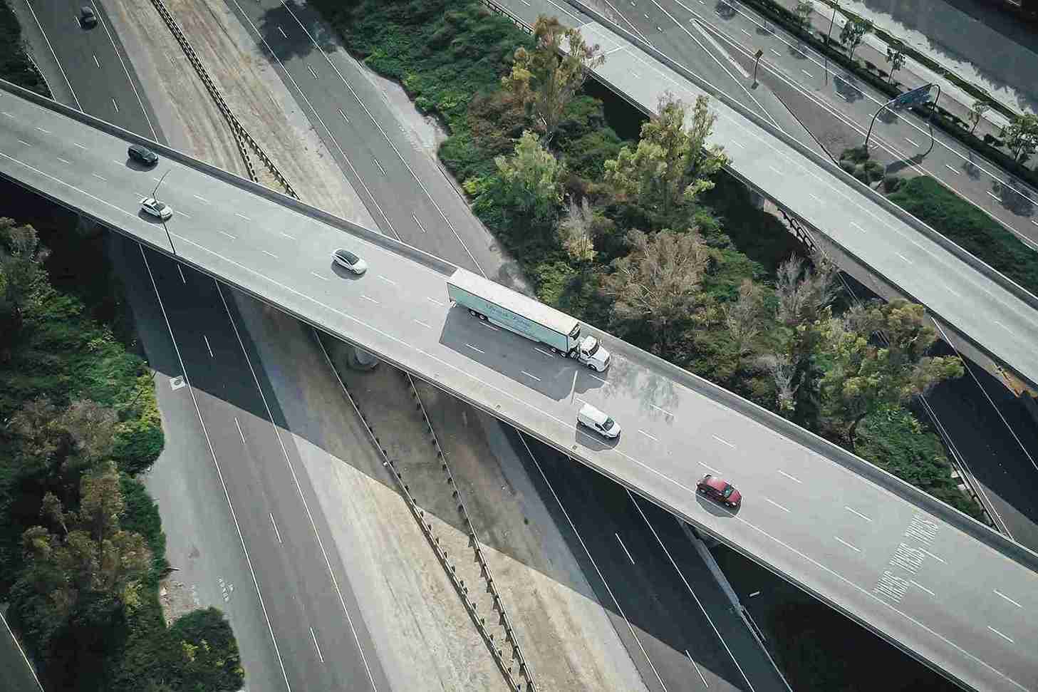 Vehículos Coches Carretera elevada con tráfico ligero_10 G2 Auto vehículos ocasión - Vista aérea de una carretera elevada con tráfico ligero, rodeada de vegetación y varios carriles de circulación.